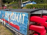 un grand panneau indiquant « Kayakmat » à côté d'une rangée de canoës