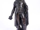 une statue antique en bronze représentant un homme portant un chapeau et un manteau