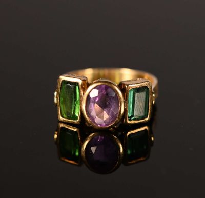 un gros plan d'une bague en or sertie d'une pierre violette et verte