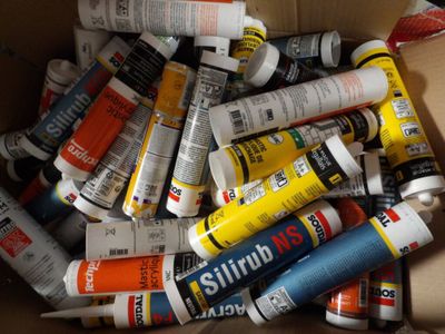 many tubes of glue in a box on the floor