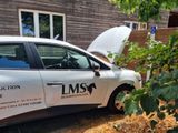 a car that is parked in front of a house with its hood open