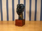 une statue représentant la tête d'une femme, posée sur un socle en bois