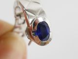 someone is holding a ring with a blue stone in it