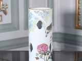 un vase orné d'un oiseau et de fleurs, posé sur une table