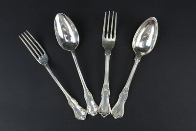 trois cuillères en argent et une fourchette sur fond noir