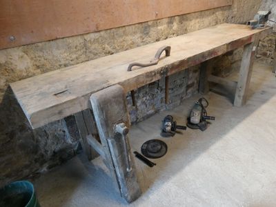 un banc en bois sur lequel sont posés des outils, dans une pièce