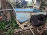 a small blue boat sitting in the yard next to a pile of junk