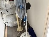 un ventilateur posé par terre à côté d'une pile de sacs
