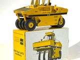 un petit camion jaune en plastique posé sur une boîte