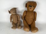 two teddy bears sitting next to each other on a white surface