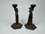 pair of bronze figurines of a woman and a man with baskets on their heads