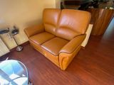 a brown leather couch in a living room next to a coffee table