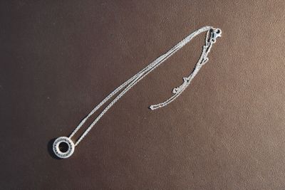 a close up of a silver necklace on a brown surface