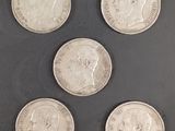 six pièces d'argent de tailles et de formes différentes sur une surface noire