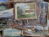 une pile de tableaux posée sur un lit recouvert d'une couette bleue