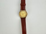 a close up of a watch on a white surface with a brown strap