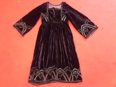 a black velvet dress with gold embroidery on the shoulders