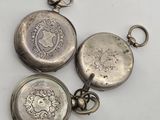 three antique silver pocket watches are sitting on a white surface