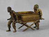 bronze figurine of two men pulling a cart with a baby