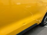 a close up of a yellow car parked in a parking lot