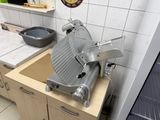 une grande trancheuse à viande posée sur un plan de travail dans une cuisine