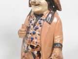 une figurine en céramique représentant un homme coiffé d'un chapeau