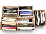 Des cartons remplis de livres sont empilés les uns sur les autres sur une surface blanche