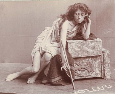 une photo d'époque montrant une femme assise sur une valise