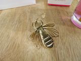 a bee brooch sitting on a table next to a box of perfume