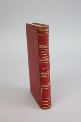 an old red book sitting on top of a table next to a white wall