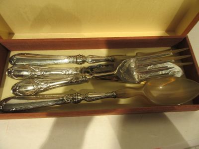 des couverts dans un coffret en bois posé sur une table avec un fond jaune