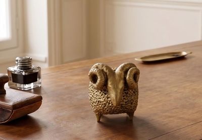a small animal figurine sitting on a table next to a pen and inkwell