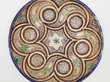 une image représentant une assiette décorative posée sur une surface blanche