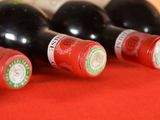several bottles of wine are lined up on a red cloth