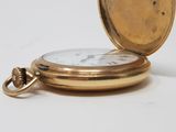 a gold pocket watch sitting on a white surface