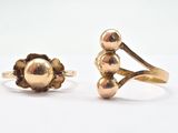 two gold rings with pearls and a flower on a white background
