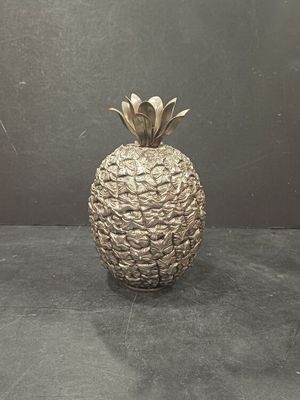 a silver pineapple shaped vase on a black table
