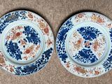 two blue and white plates with floral designs on them on a brown surface