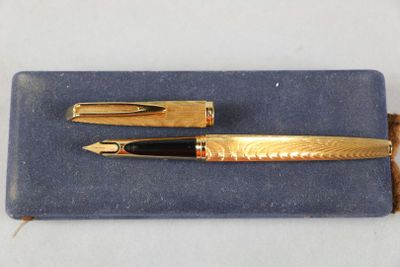 a gold pen and a black pen sitting on a blue cloth