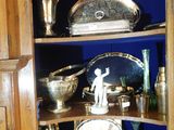une armoire d'angle sur laquelle sont disposés de nombreux objets en argent