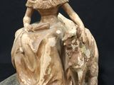 a statue of a woman sitting on a rock with a dog