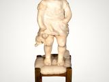 statue of a child sitting on a stool with a teddy bear