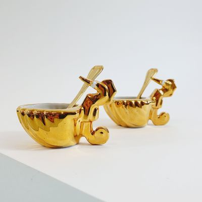 pair of gold plated baby stroller cups on a white surface