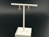 a pair of earrings on a white stand with a tag