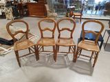 Quatre chaises en bois sont disposées en cercle dans une pièce.