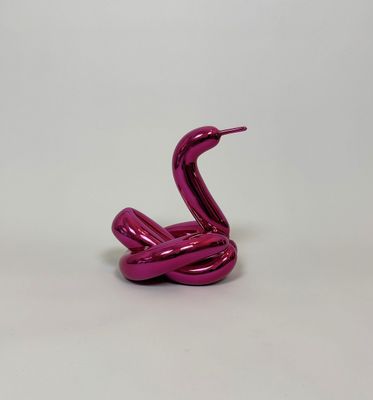 a close up of a pink sculpture of a snake on a white surface