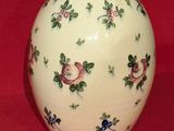 a white vase with flowers on it sitting on a red cloth