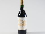 a bottle of red wine sitting on top of a white table