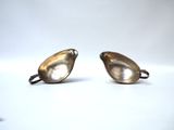 pair of silver spoons sitting on top of each other on a white surface