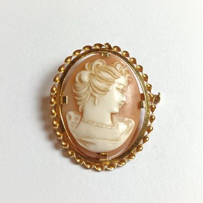une image représentant une femme portant une broche en or